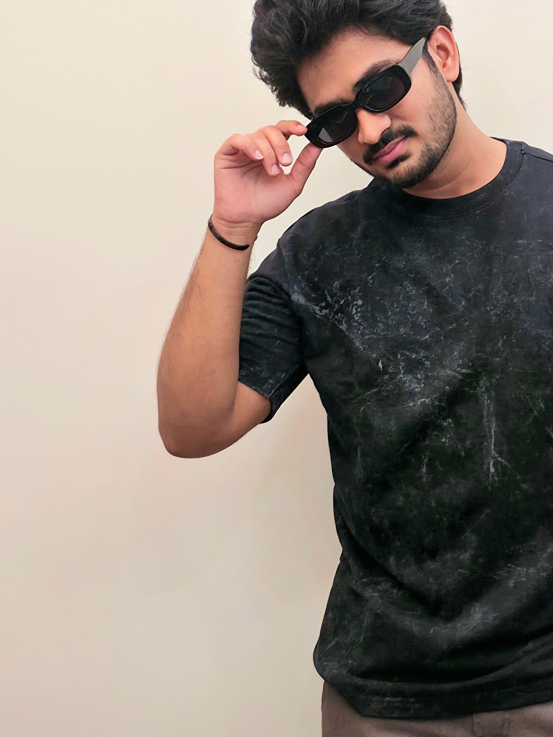 Man wearing a black tie-dye t-shirt against a beige background
